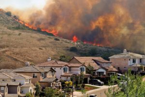 Flames and smoke from a wildlife fill the sky bedhind a Southern California Subdivision. A recent southern california brush fire burning extremely close to homes.