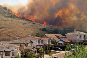 Flames and smoke from a wildlife fill the sky bedhind a Southern California Subdivision. A recent southern california brush fire burning extremely close to homes.